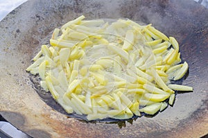 Large frying pan with potatoes in nature in winter