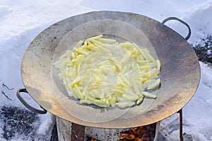 Large frying pan with potatoes in nature in winter