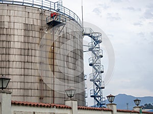 Large fuel tanks. Tanks and ladders of the tank farm. The gloomy atmosphere of an industrial area