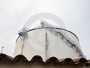 Large fuel tanks. Tanks and ladders of the tank farm. The gloomy atmosphere of an industrial area. Oil storage