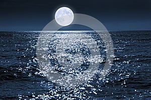 Large Full Blue Moon Rises Brightly Over a Calm Ocean Scene