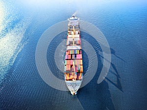 Large full loaded container ship sailing high seas. Aerial front view