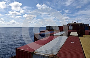 Large, fully loaded, cargo container ship sailing through the ocean.