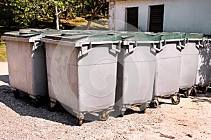 Large garbage containers, trash dumpsters and bins standing in row. Orderly stowed garbage cans.