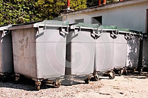 Large garbage containers, trash dumpsters and bins standing in row. Orderly stowed garbage cans ready for separate garbage.