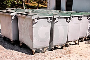 Large garbage containers, trash dumpsters and bins standing in row. Orderly stowed garbage cans ready for separate garbage.