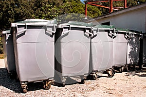 Large garbage containers, trash dumpsters and bins standing in row. Orderly stowed garbage cans ready for separate garbage.