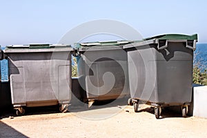 Large garbage containers, trash dumpsters and bins standing in row. Orderly stowed garbage cans ready for separate garbage.