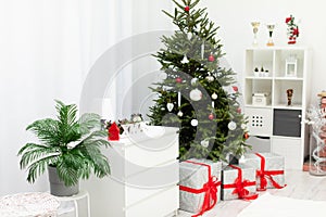 Large gifts lying under a decorated Christmas tree in a bright room