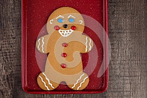 Large gingerbread cookie on a red cookie sheet on a wood table