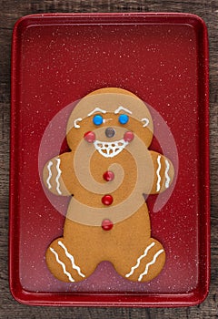 Large gingerbread cookie on a red cookie sheet on a wood table