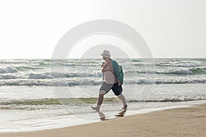 A large girl walks along the edge of the water