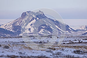 A large glacial mountain in the countryside of Iceland with a steppe in front of it.