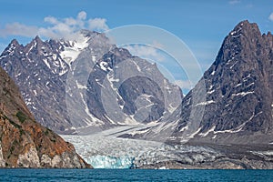 Large glacier flowing down mountain side to the sea at Evighedsfjord, Greenland