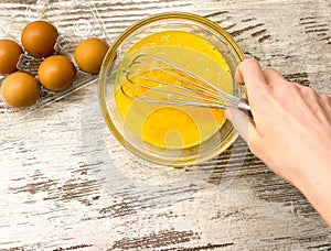 A large glass bowl with a process of beating eggs for cooking.