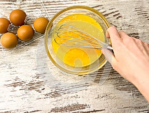 A large glass bowl with a process of beating eggs for cooking. photo