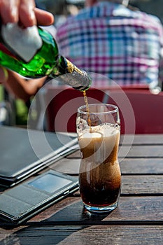 A large glass of dark beer on a pub background on a wooden table. The vertical frame