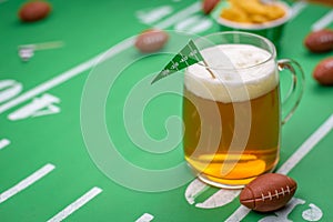 Large glass mug of cold beer on table with superbowl party decor