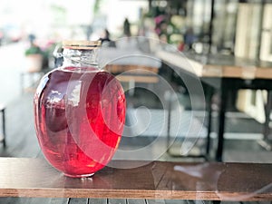 A large glass three-liter can of campote, juice, potions with a glowing liquid with a wooden lid on a blurred background on a shel