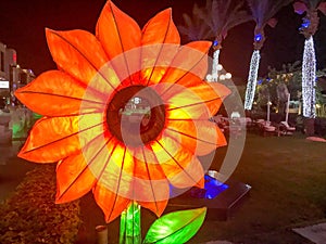 Large glowing light bulbs bright yellow paper decorative artificial sunflower flower with petals festive decoration in a nightly f