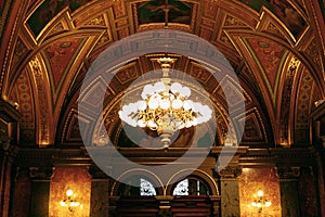 Large golden chandelier under the gilded ceiling in the interior.