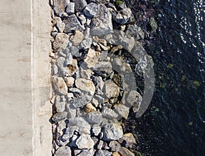 Large granite stones on the river bank. The edge of the river bank, water, road