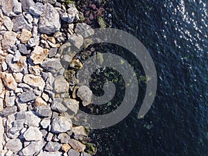 Large granite stones on the river bank. The edge of the river bank, water, road