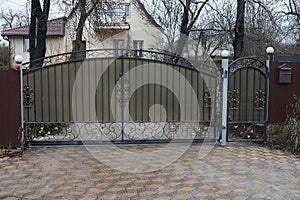 Large gray metal gate with a black wrought iron pattern on the profile