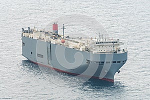 Large gray roll-on/roll-off RORO or ro-ro ships or oceangoing vehicle carrier ship anchor in the open sea.