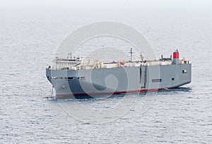 Large gray roll-on/roll-off RORO or ro-ro ships or oceangoing vehicle carrier ship anchor in the open sea.