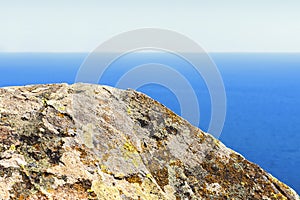 Large gray stone against the background of a blue sea and a clear sky