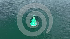 Large green buoy with solar panelsin the sea.