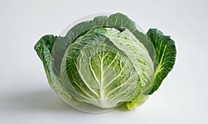 A large green cabbage is sitting on a white surface