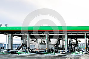 Large green industrial gas station for refueling vehicles, trucks and tanks with fuel, gasoline and diesel in the winter