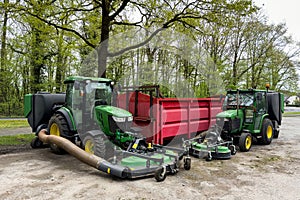 Large green lawn mowers standing near a metal red container.