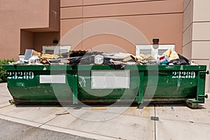 Large green metal dumpster filled with garbage from building renovation - Fort Lauderdale, Florida, USA