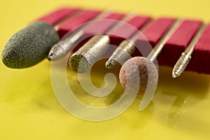 Large green nail cutter on a light yellow background. The tool is used by manicurists when removing burrs on the fingers.