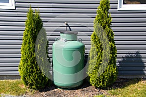 A large green propane tank on the side of a house