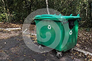 Large green recycle bin on the street of a park photo