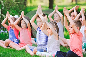 A large group of children engaged in yoga in the Park sitting on the grass