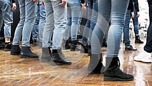 Large group of children synchronously dance in blue jeans and black boots. training