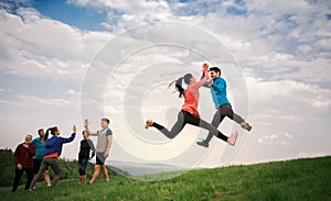 Large group of fit and active people jumping after doing exercise in nature.