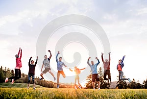 Large group of fit and active people jumping after doing exercise in nature. photo