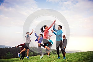 Large group of fit and active people jumping after doing exercise in nature.