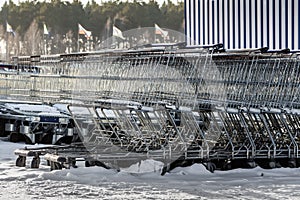 A large group of gray metal shopping storage baskets outside in the snow in winter by the supermarket