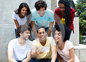 Large group of international young adult people looking at mobil