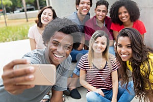 Large group of international young adults taking selfie with phone