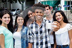 Large group of international young adults taking selfie with phone outdoor in the summer