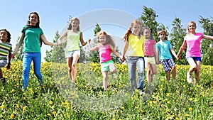 Large group of kids run in dandelion field
