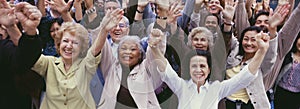 Large group of multi-ethnic people cheering with arms raised